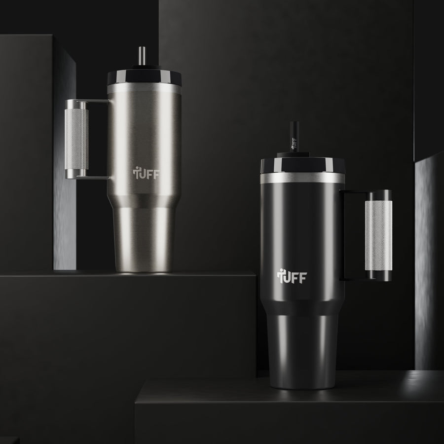 The Tuff Tumbler in stainless and in black, standing on dark blocks