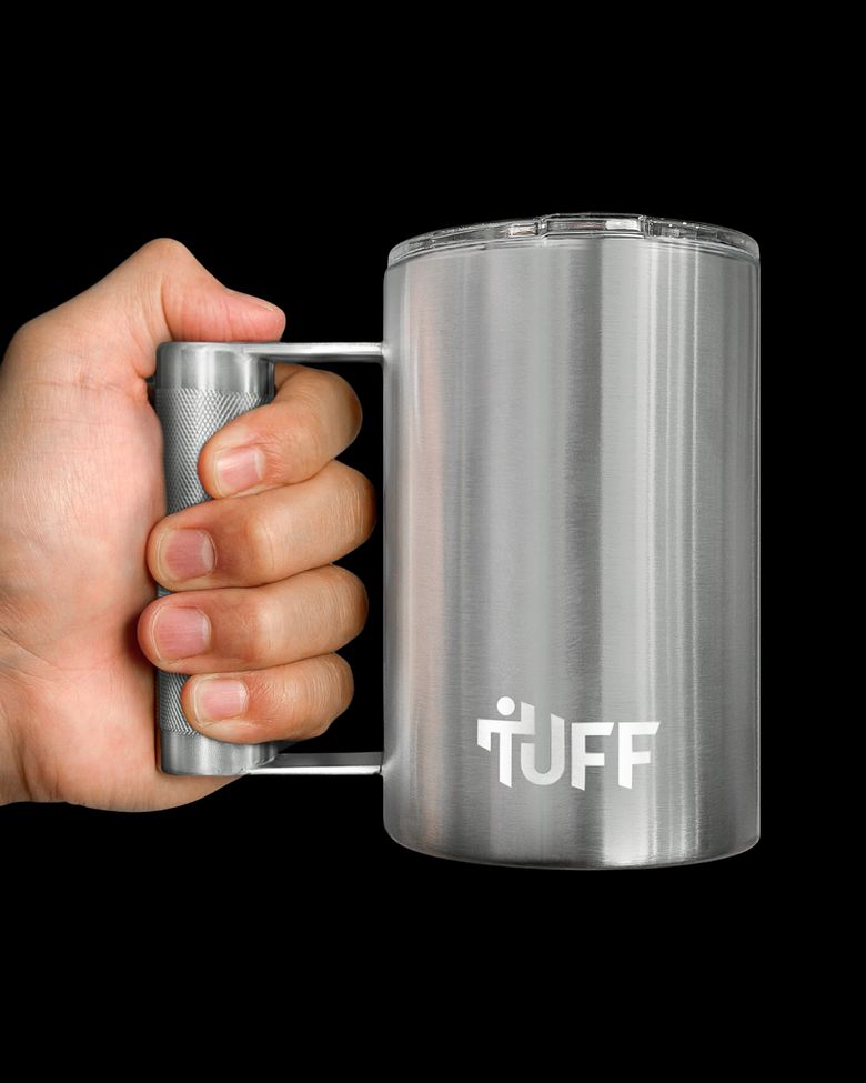 A hand closed fully around the knurled barbell handle, all four fingers through, knuckles clear of the mug body.