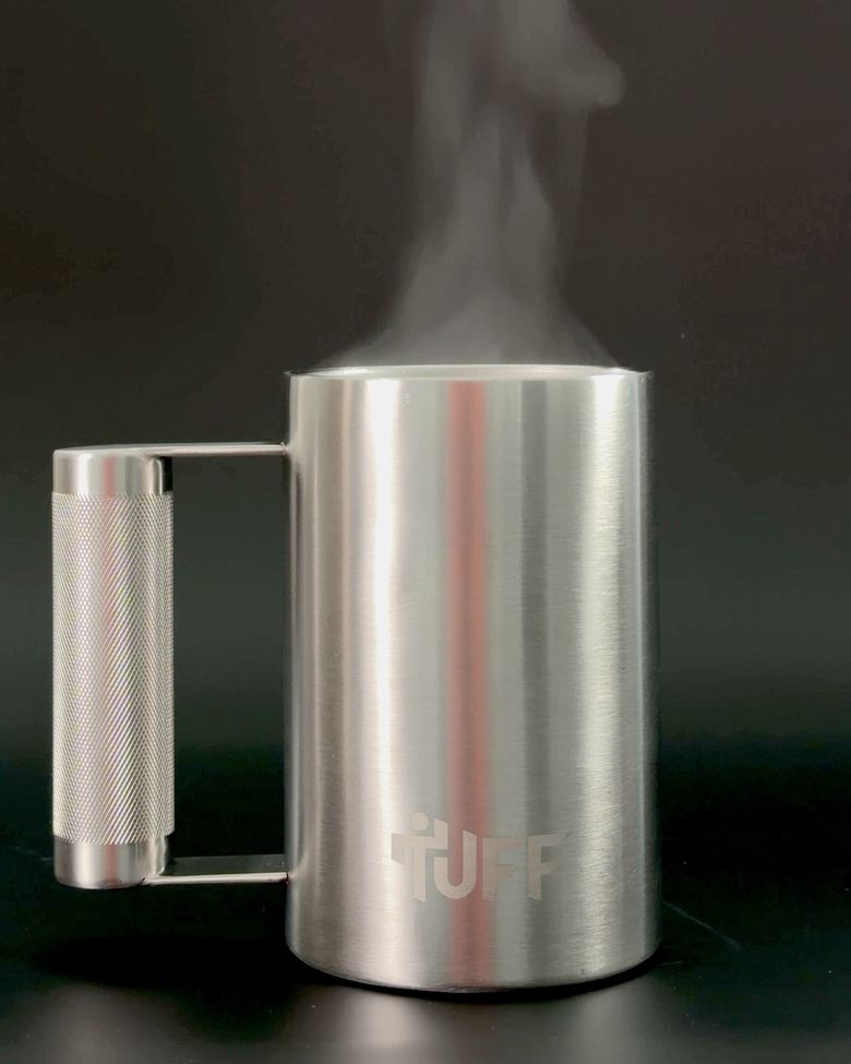 Real steam rising off coffee in the silver Tuff Mug on a dark studio surface.