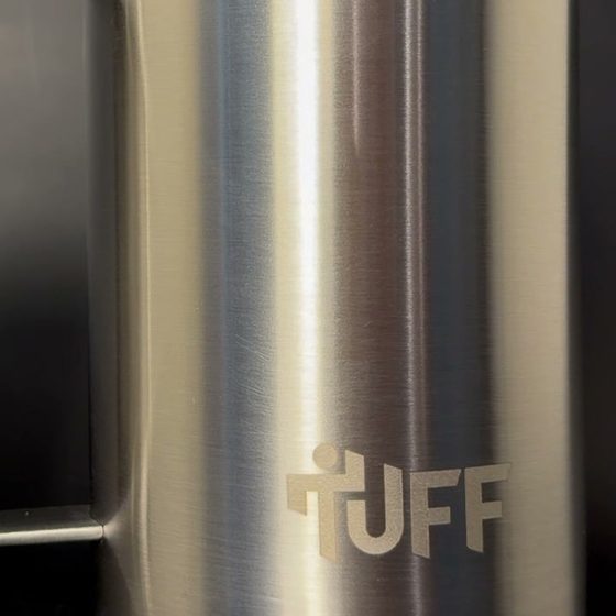 Macro of the TUFF mark laser-engraved into the brushed steel body.